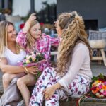 Famiglia omogenitoriale con figlia sorridente e mazzi di fiori, simbolo di affetto e riconoscimento legale del ruolo di entrambe le madri come genitori
